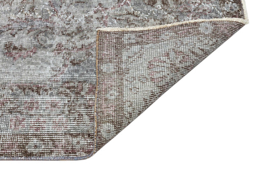 Load image 1 in gallery view. Grey and brown distressed traditional rug with a floral medallion pattern, shown with a corner folded over.