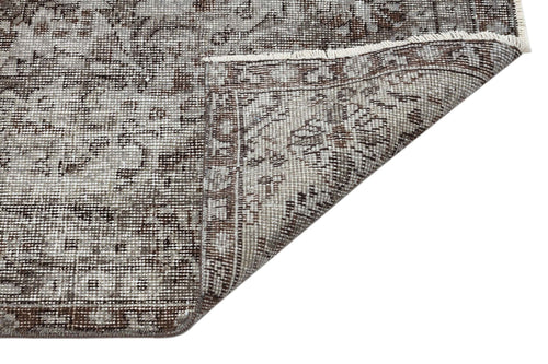 Load image 1 in gallery view. Grey and brown distressed traditional rug with a floral medallion pattern, shown with a corner folded over.