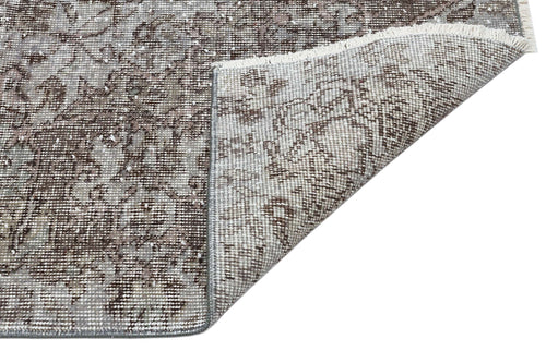 Load image 1 in gallery view. Brown and grey distressed traditional rug with a floral medallion pattern, shown with a folded corner revealing the backing.