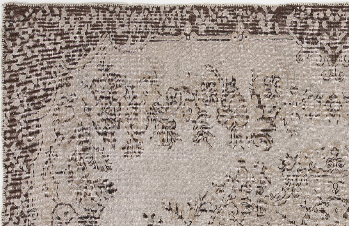 Beige and dark brown rug with a distressed floral medallion pattern and a decorative border.