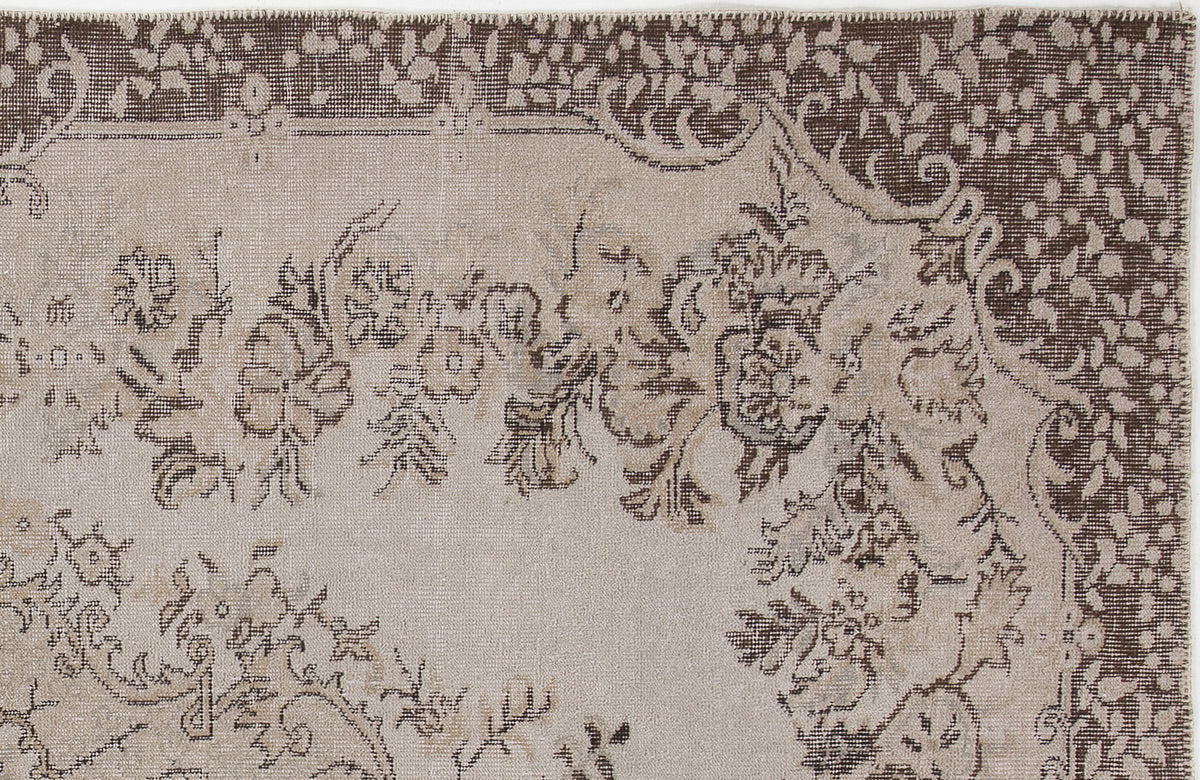 Beige and dark brown rug with a distressed floral medallion pattern and a decorative border.