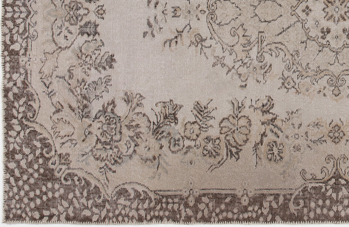 Beige and brown rug with a distressed floral medallion pattern and a detailed decorative border.
