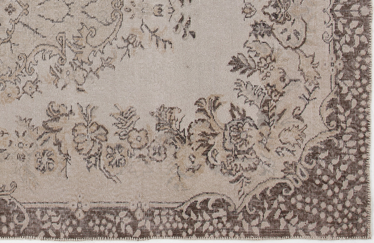 Beige and brown rug with a distressed floral medallion pattern and a wide decorative border.