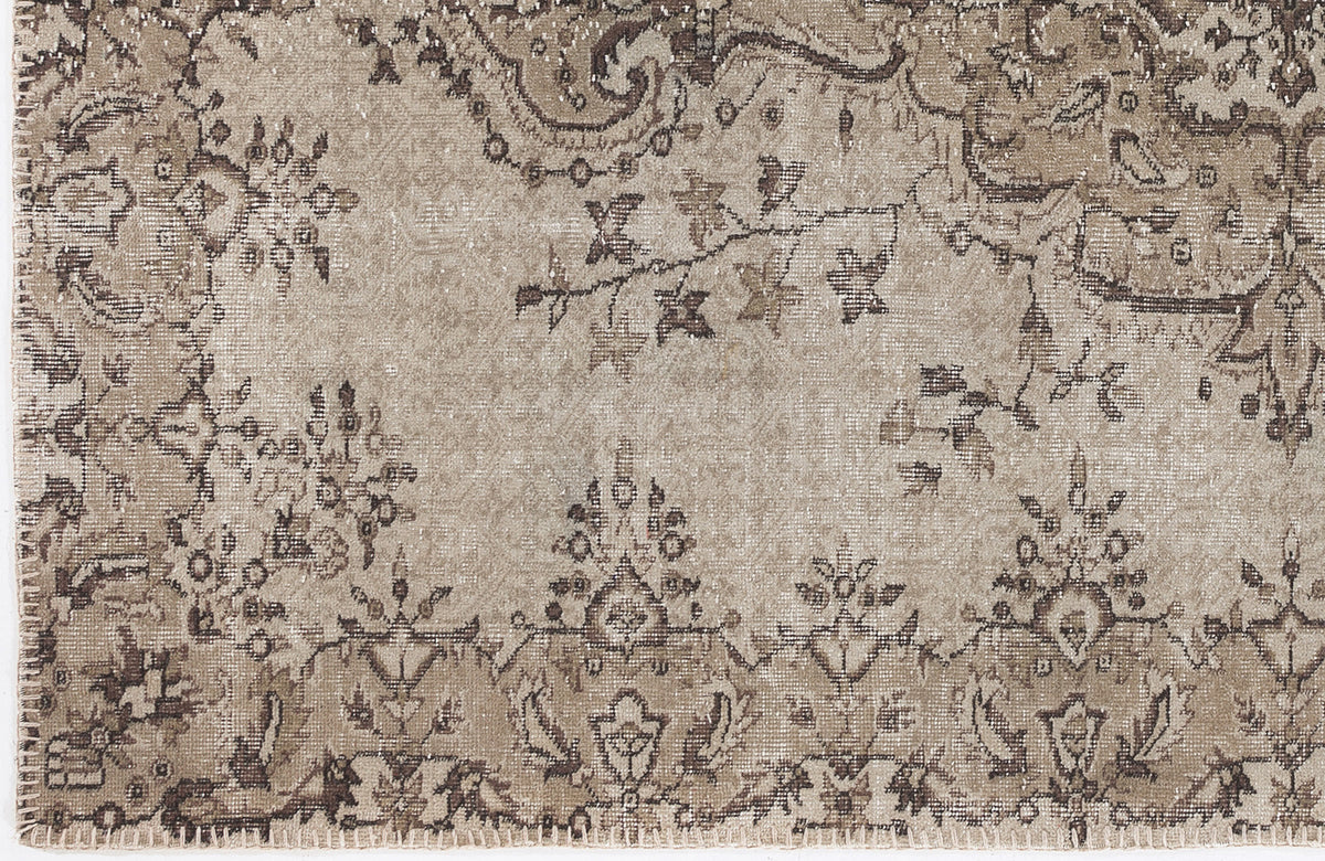 Beige and brown distressed rug with a traditional floral medallion and vine pattern.