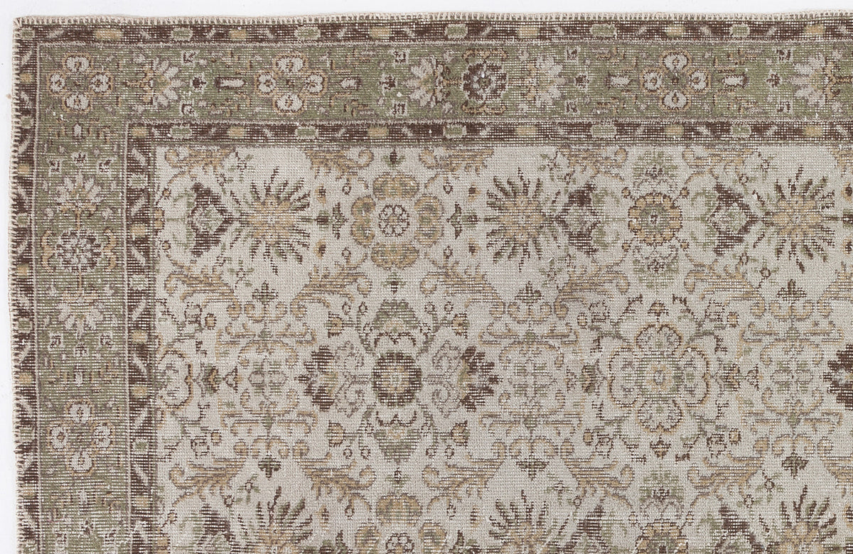 Beige, sage green, and brown traditional rug with a distressed floral medallion pattern and a decorative border.