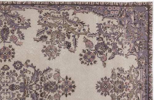 Load image 1 in gallery view. Beige rug with a distressed purple and brown floral medallion pattern and a dark brown stitched border.