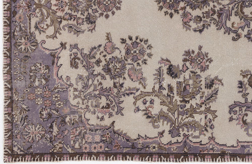 Load image 1 in gallery view. Beige rug with a distressed floral medallion pattern in muted purple, brown, and pink tones.
