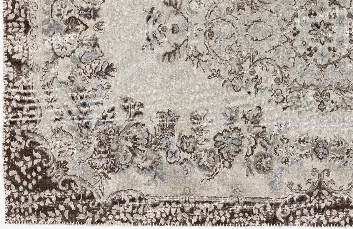 Beige rug with a distressed brown and light blue floral medallion pattern and ornate border.