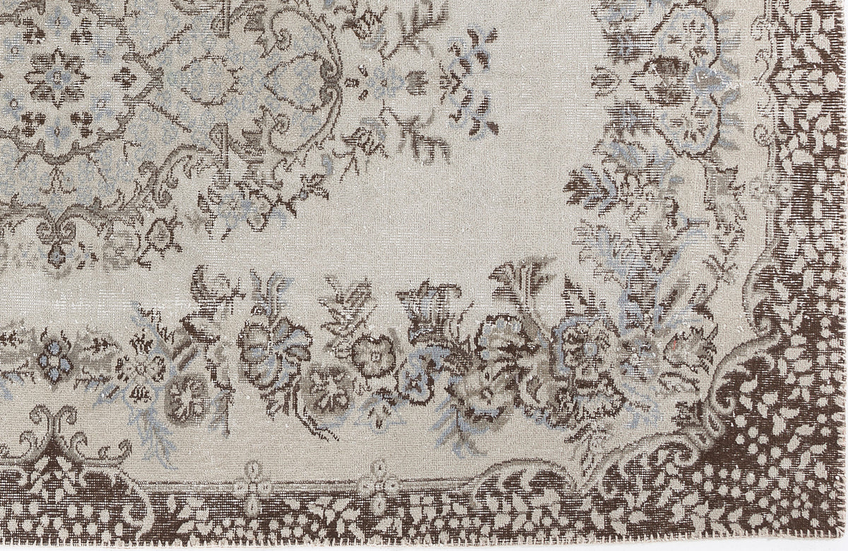 Beige rug with a distressed floral medallion pattern in brown and slate blue.
