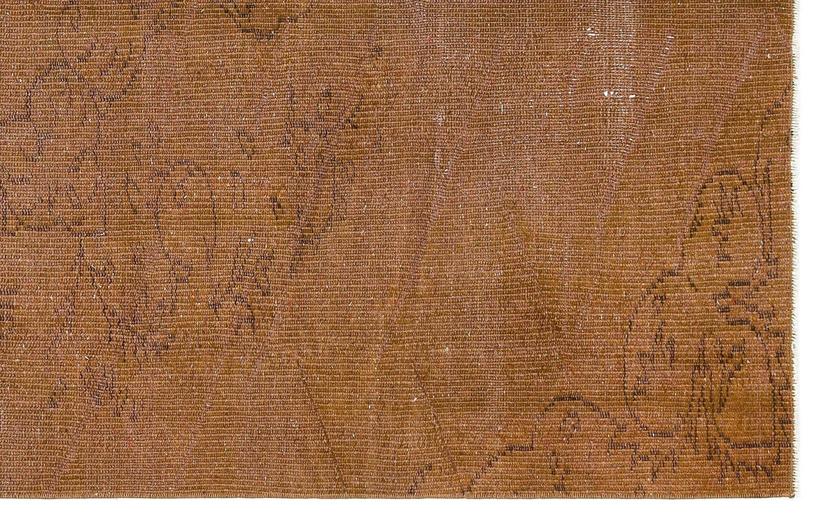 Distressed tobacco-brown rug with a faint, dark linear floral pattern and visible woven texture.