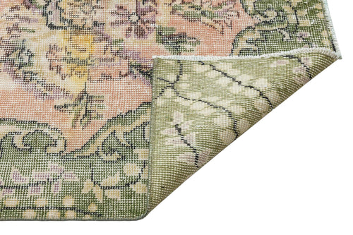 Load image 1 in gallery view. Distressed floral rug in sage green, peach, and yellow with a folded corner revealing the woven backing.