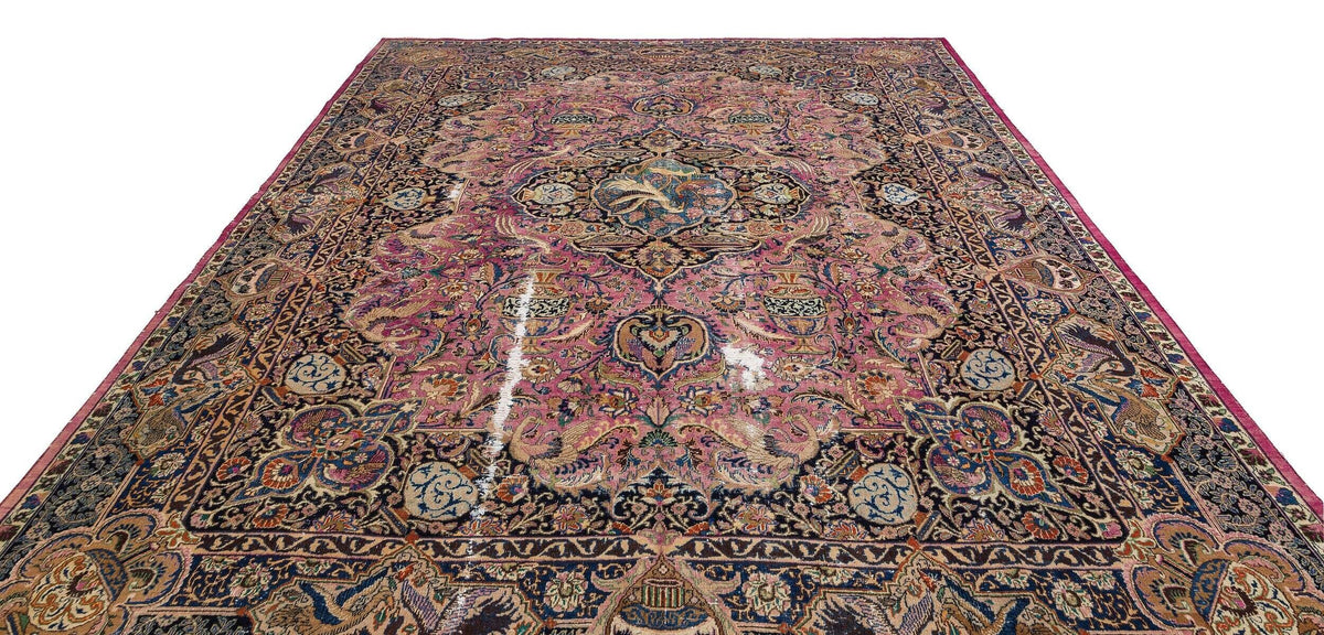 Pink and navy blue traditional Persian-style rug with an intricate floral medallion pattern on a white background.