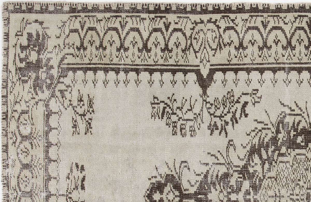 Beige and dark brown rug with a distressed traditional border and central floral motif.