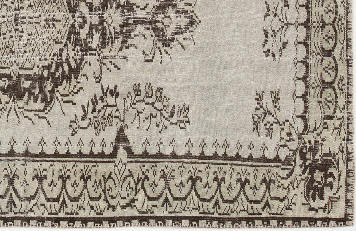 Beige and dark brown rug with a traditional ornate border and floral medallion pattern.