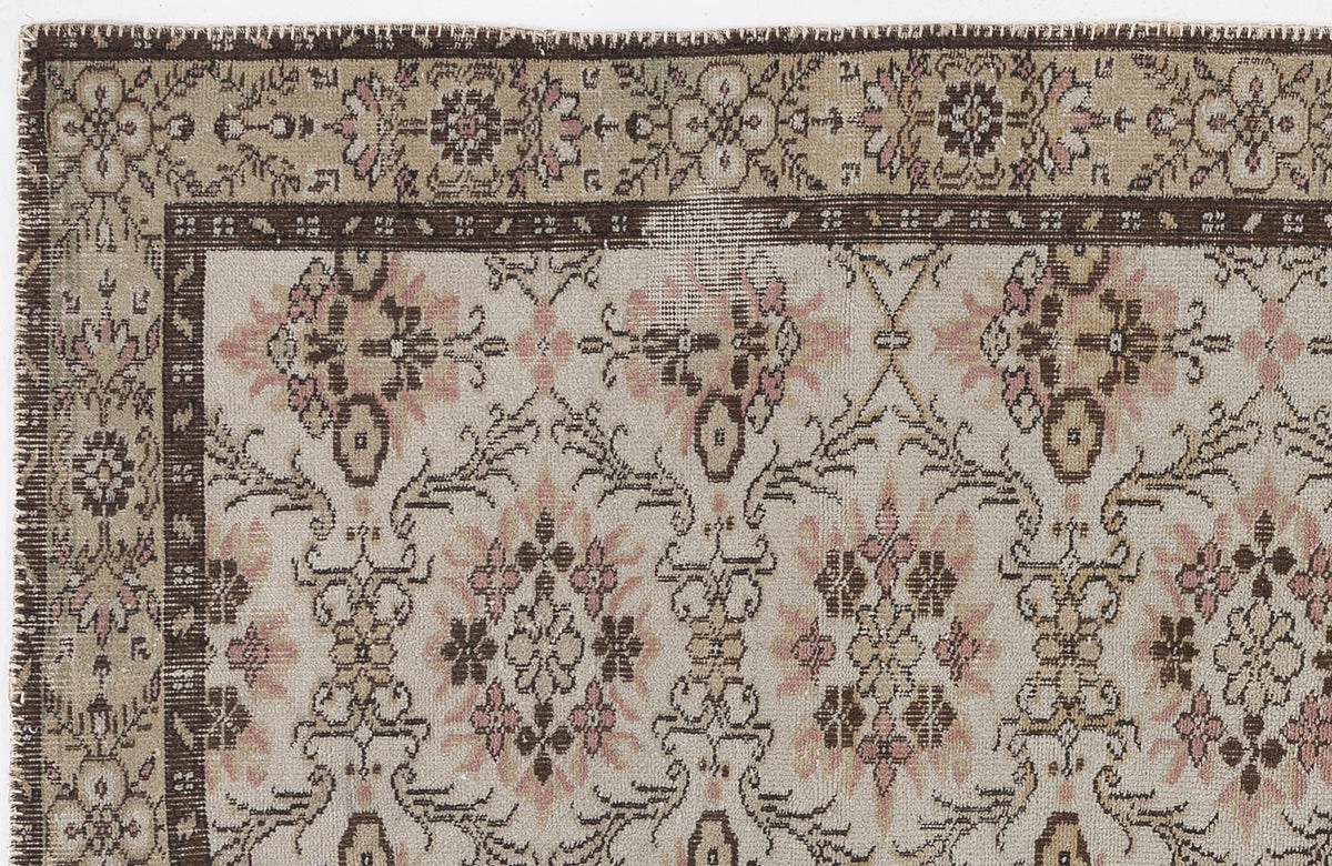 Beige, brown, and muted pink vintage-style rug with a floral medallion border and repeating botanical pattern.