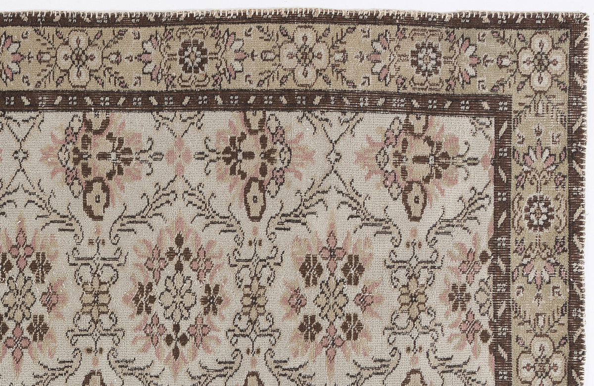 Beige, brown, and muted pink traditional rug with a floral medallion pattern and a wide decorative border.