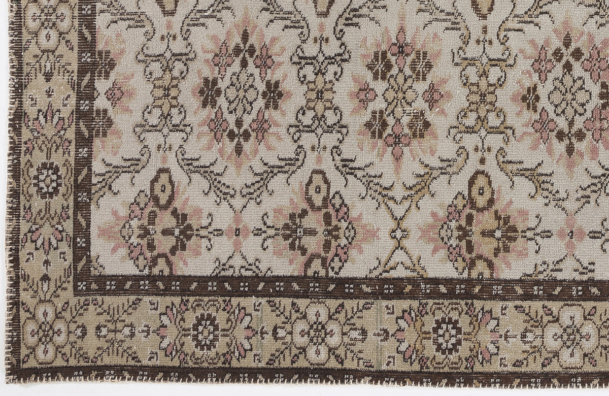 Beige rug with a brown and pink floral medallion pattern and a dark brown decorative border.