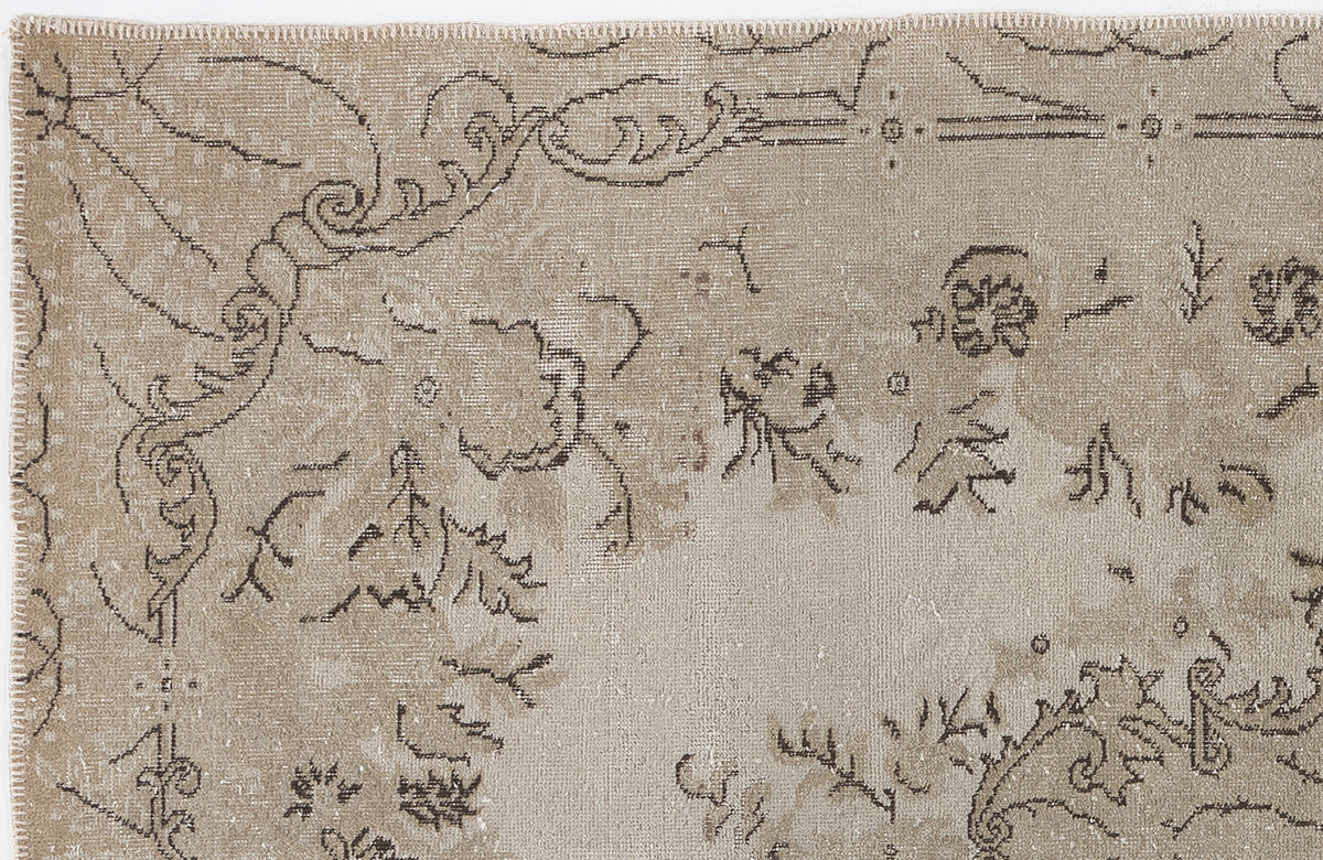 Beige and taupe distressed rug with a faded, intricate floral and scrollwork pattern.