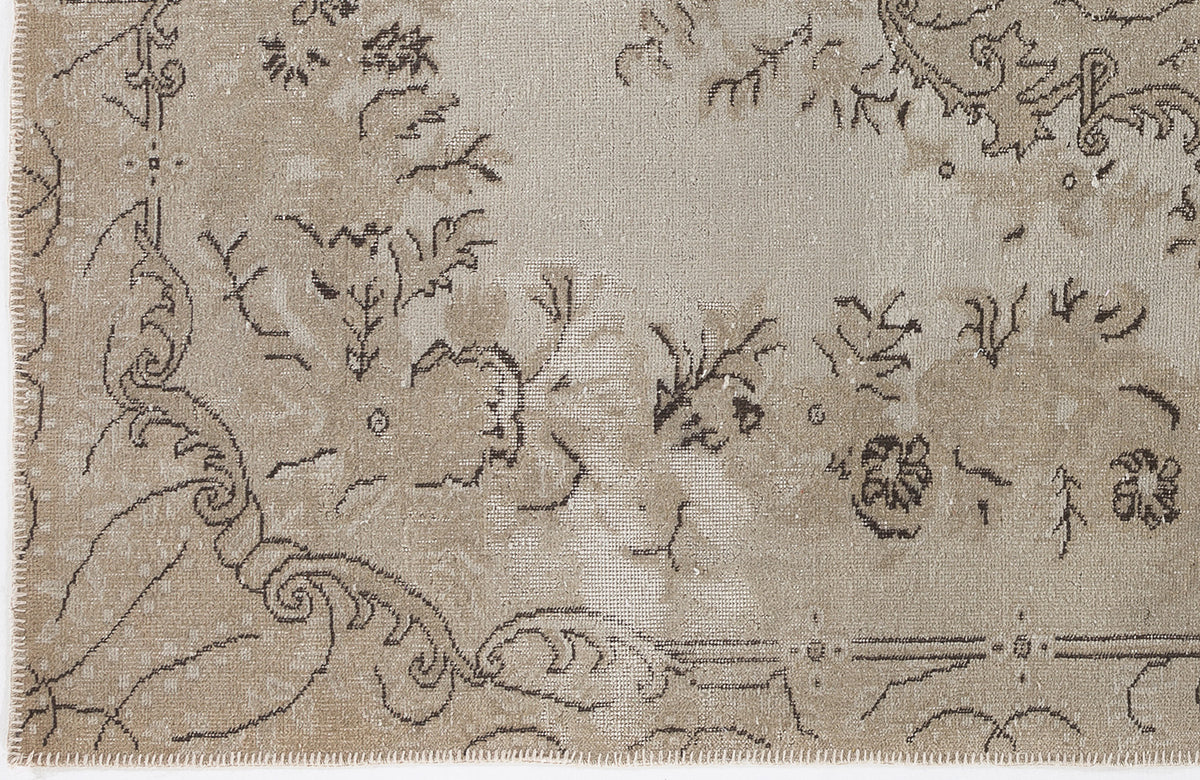 Beige and taupe distressed rug with a faded traditional floral medallion pattern and a stitched edge.