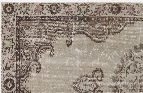 Load image 1 in gallery view. Beige and brown distressed rug with a traditional floral medallion border and faded ornate patterns.