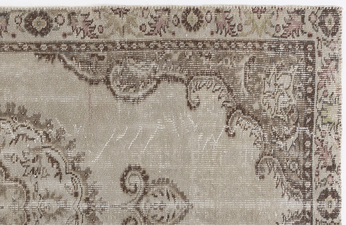 Distressed beige and brown rug with a faded traditional floral medallion pattern and a decorative border.