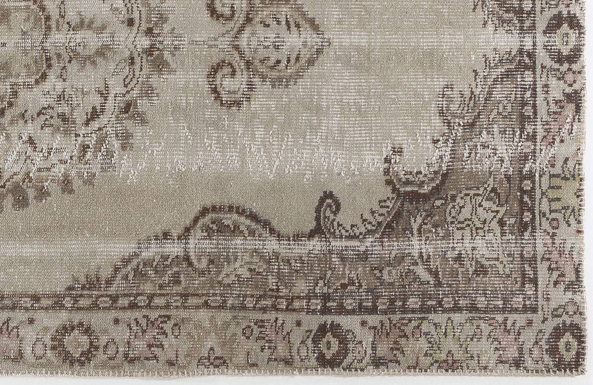 Taupe and brown distressed rug with a faded traditional floral medallion pattern.