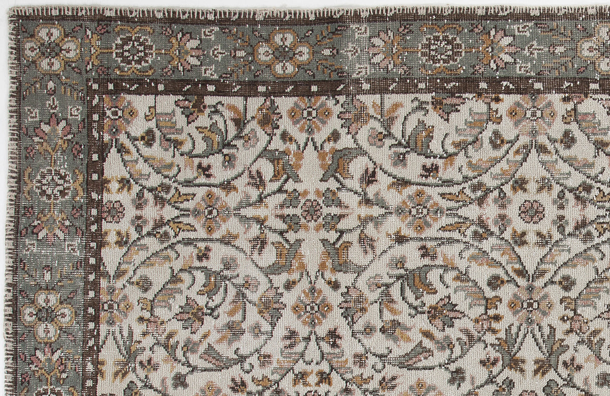 Cream, sage green, and brown traditional rug with a floral vine pattern and a decorative border.