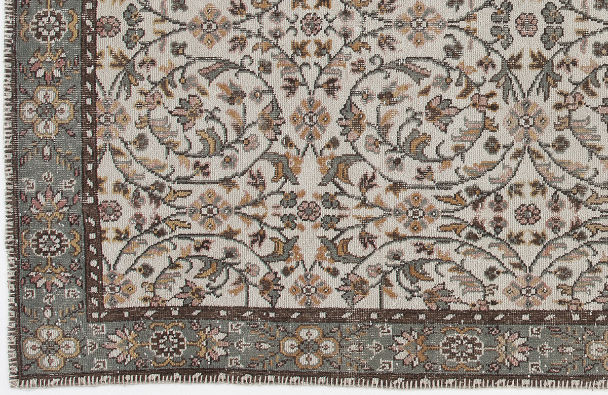 Cream rug with a traditional floral medallion pattern in sage green, brown, and muted pink, featuring a detailed border.