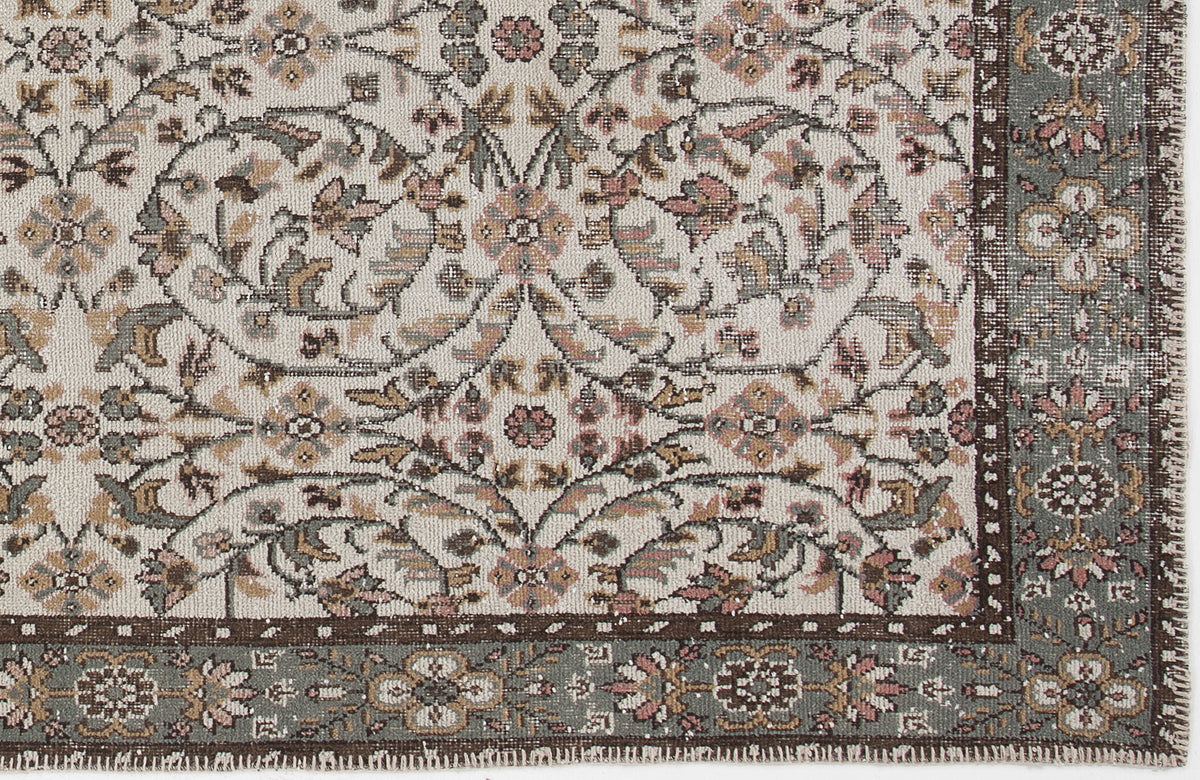 Cream, sage green, and dusty rose traditional rug with a floral vine pattern and a dark brown border.