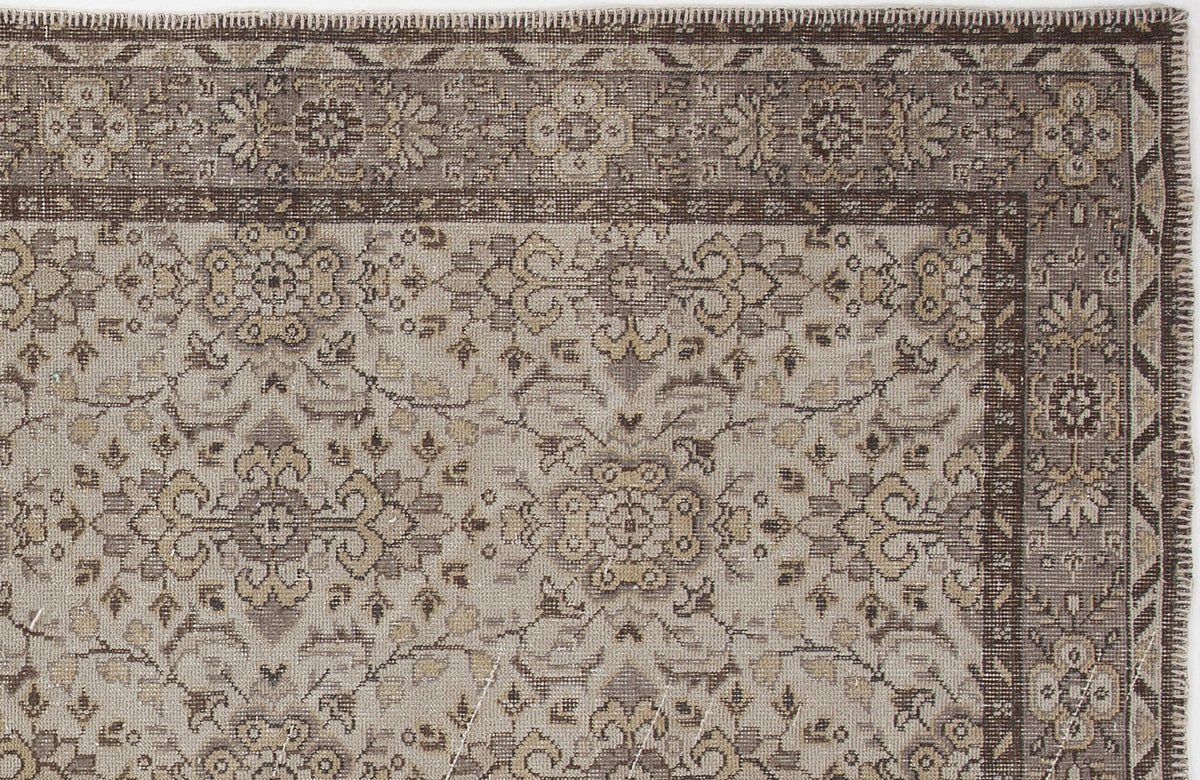 Taupe and brown traditional rug with a distressed floral medallion pattern and a geometric border.