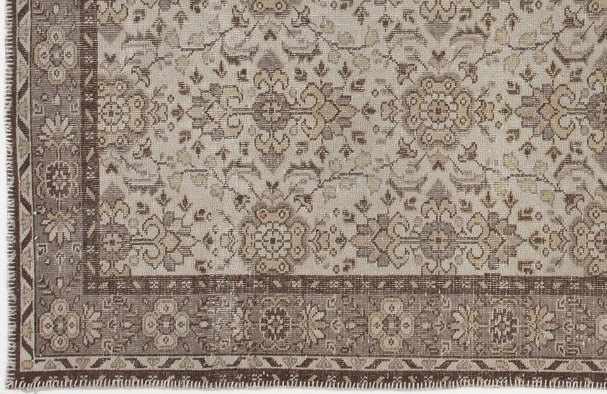 Beige and brown traditional rug with a distressed floral medallion pattern and a detailed geometric border.