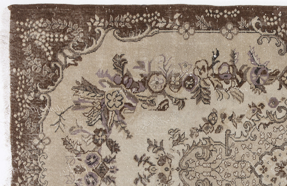 Distressed brown and beige rug with a traditional floral medallion pattern and a wide decorative border.