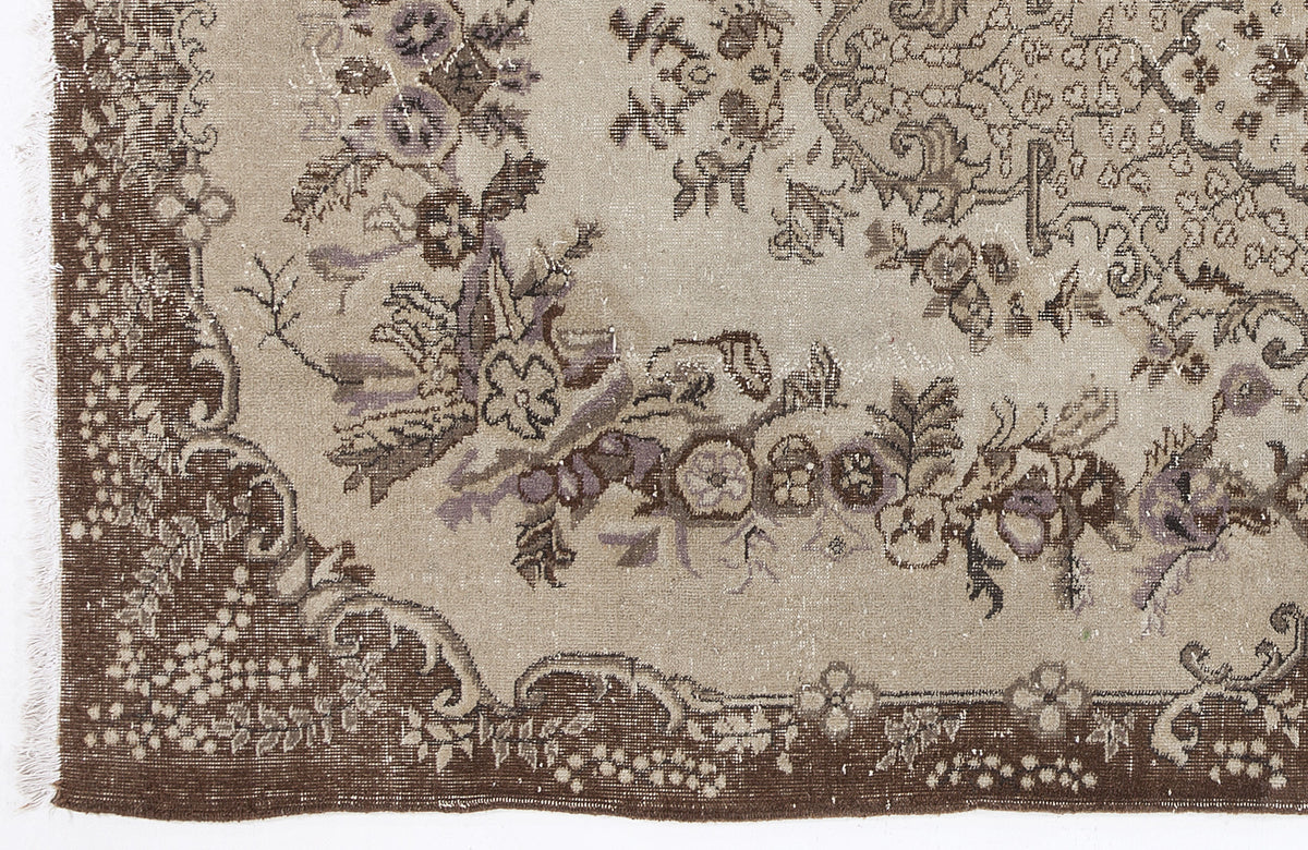 Distressed beige rug with brown and muted purple floral medallion patterns and a decorative border.