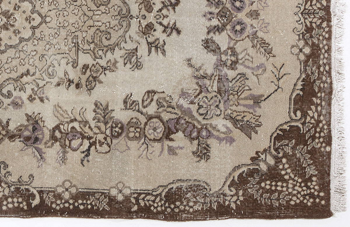 Beige and brown vintage-style rug with a distressed floral medallion pattern and fringed edge.
