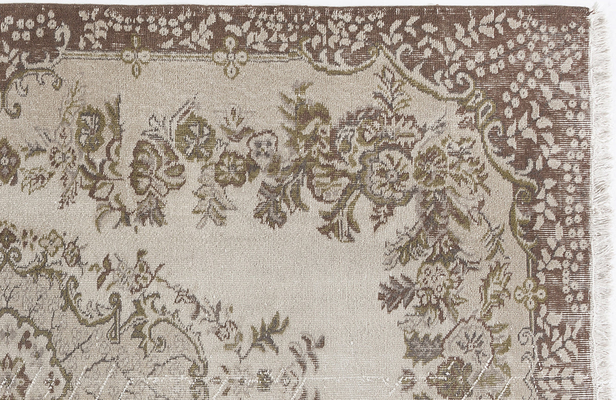 Beige and brown traditional rug with a floral medallion pattern and a fringed edge on a white background.