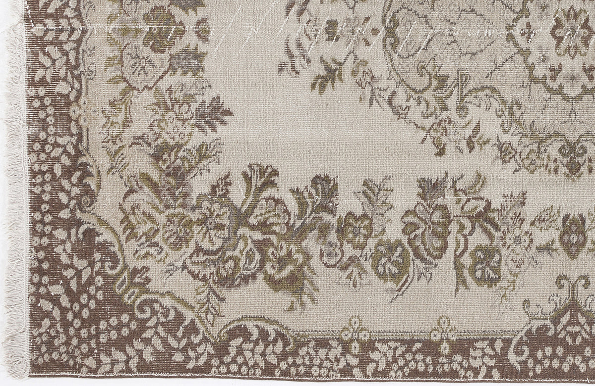 Beige and brown distressed rug with a traditional floral medallion pattern and fringed edge.