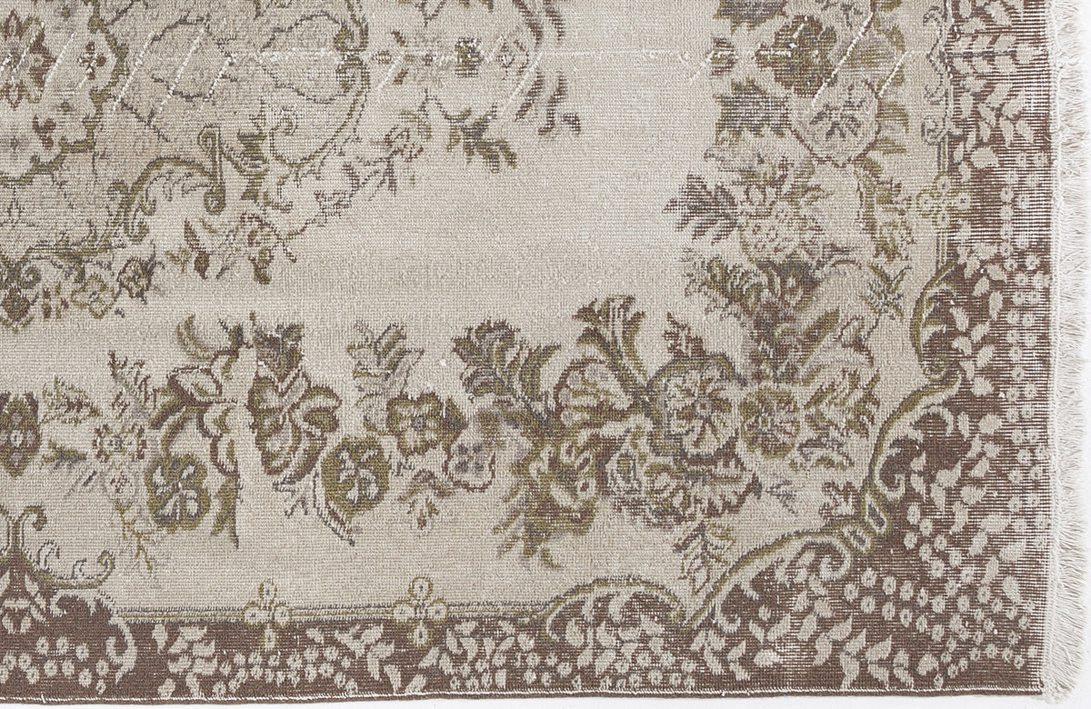 Beige and brown traditional rug with a distressed floral medallion pattern and fringed edge.