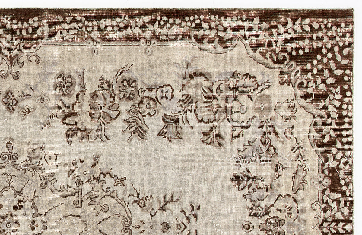 Beige and brown vintage-style rug with a distressed floral medallion pattern and a wide decorative border.