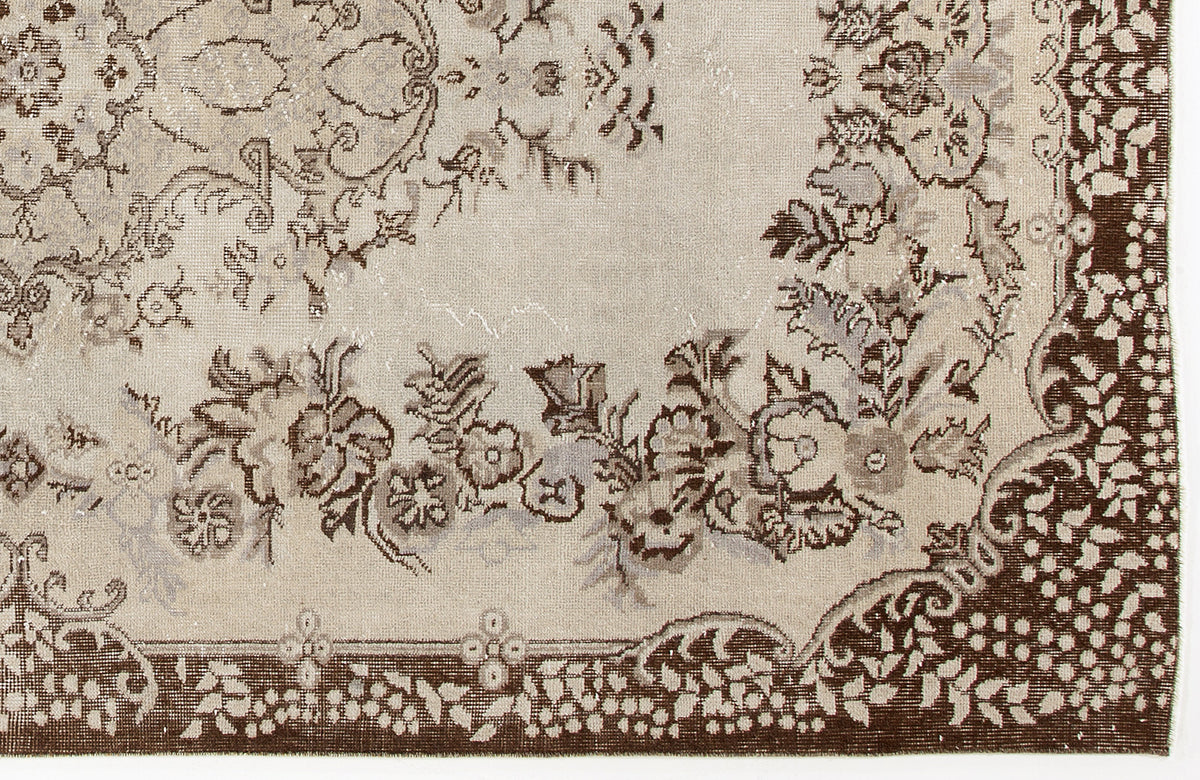 Beige and brown rug with a distressed floral medallion pattern and a decorative border.