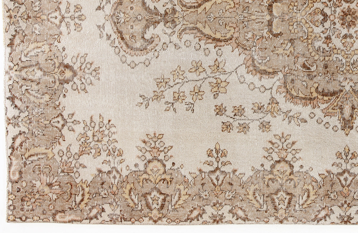 Beige and brown traditional rug with a distressed floral medallion and vine pattern.