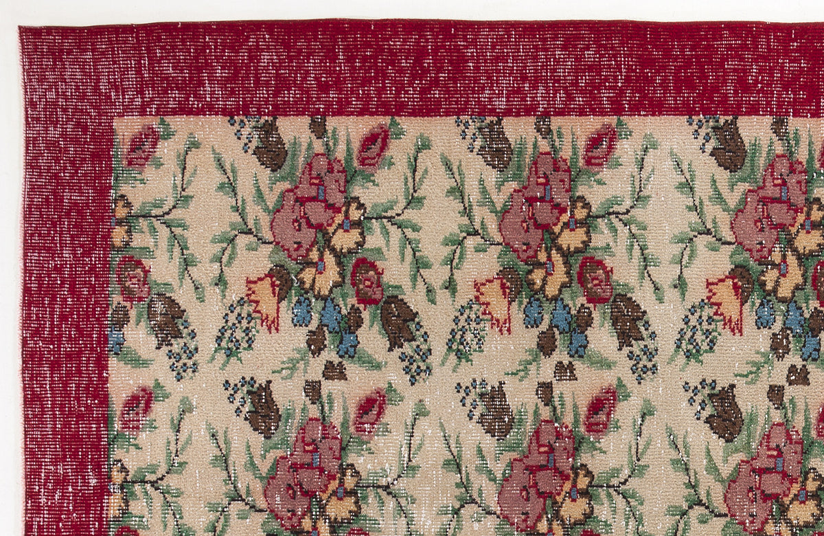 Beige rug with a red border and a repeating floral pattern in red, green, blue, and yellow.