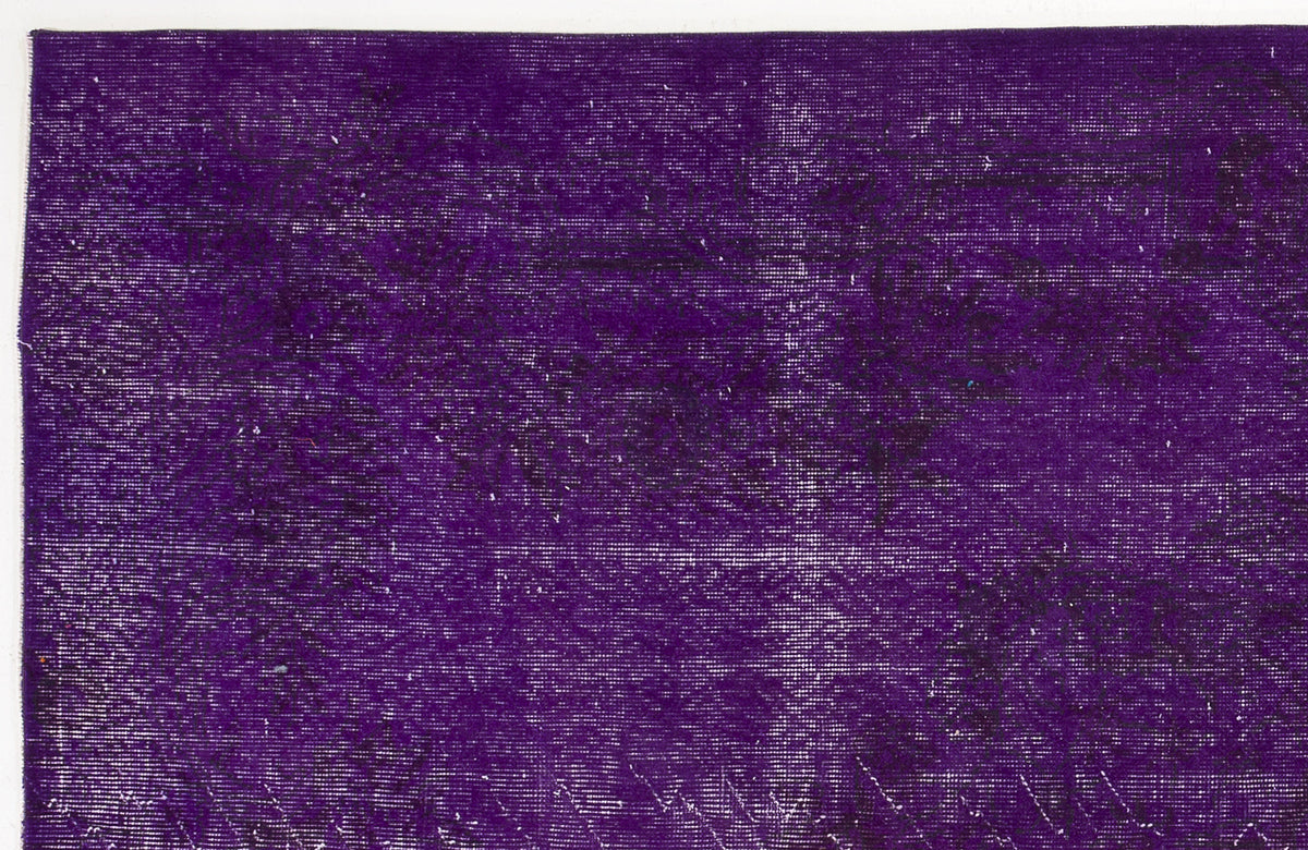 Deep purple vintage-style rug with a distressed, faded texture and subtle dark ornamental patterns.