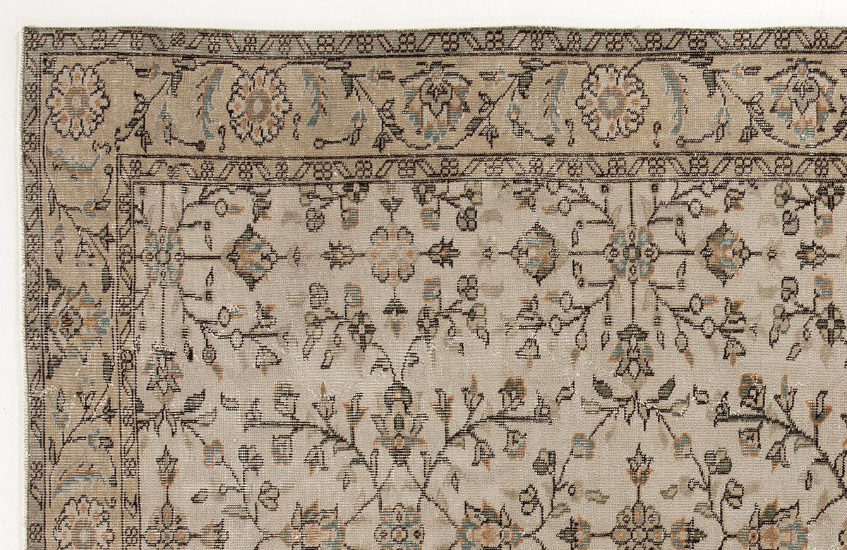 Beige traditional rug with a distressed floral vine pattern in muted blue, grey, and orange accents.