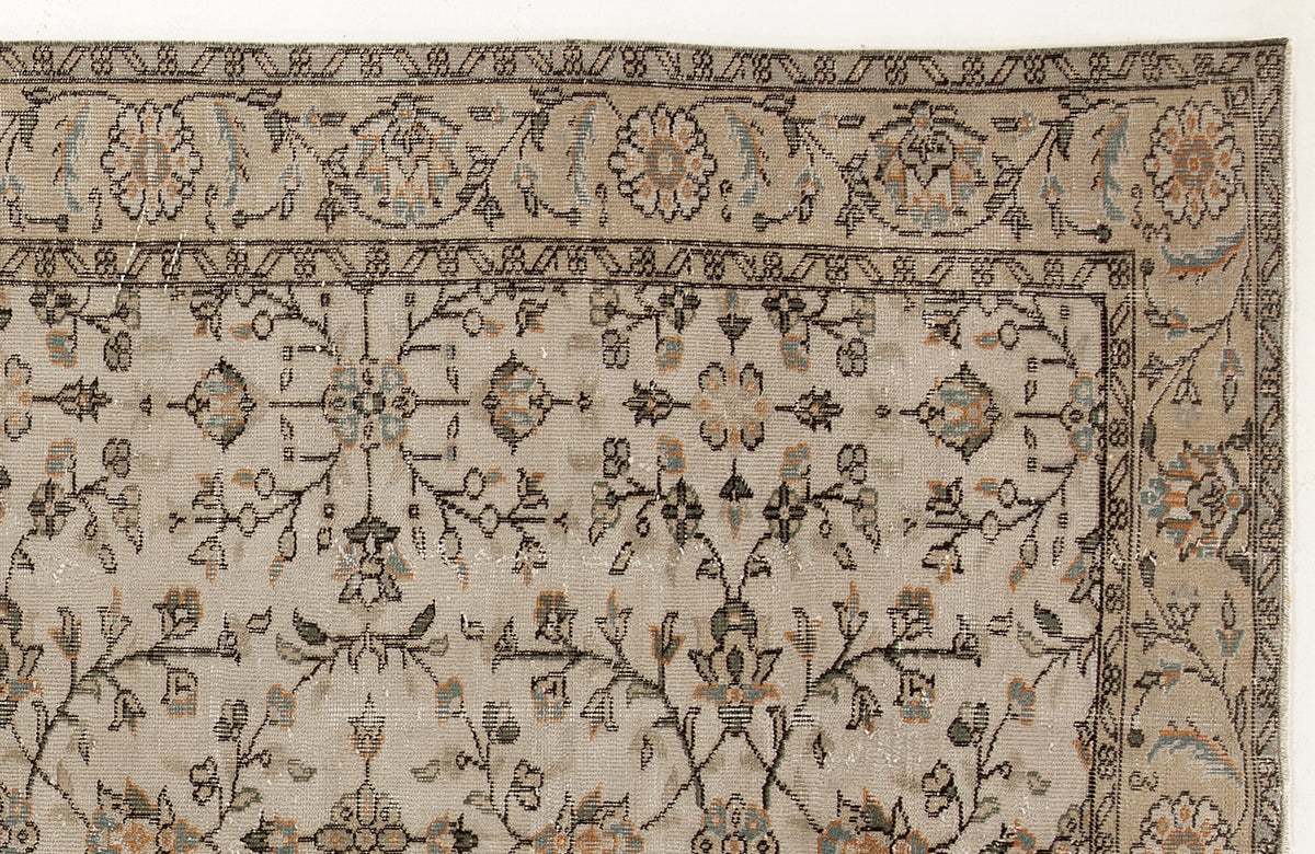 Beige traditional rug with a distressed floral vine pattern in muted blue, orange, and charcoal accents.