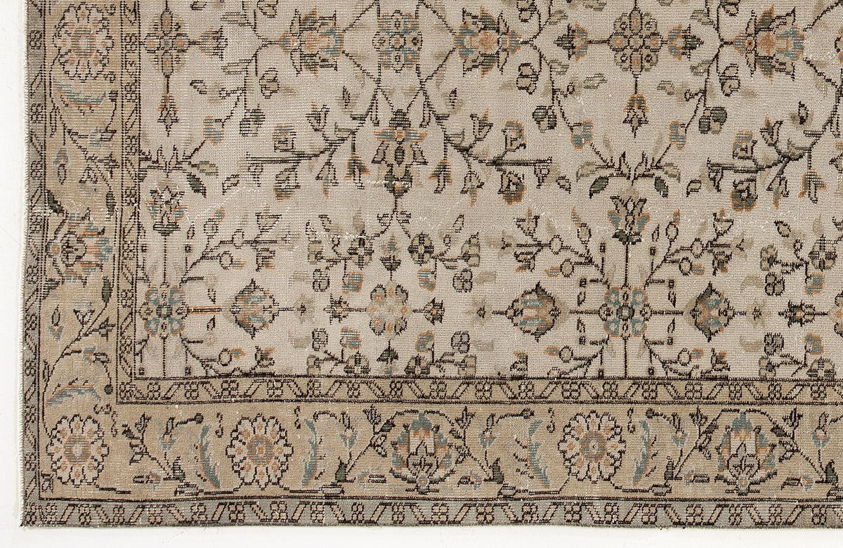 Beige traditional rug with a distressed floral vine pattern in muted blue, orange, and charcoal accents.