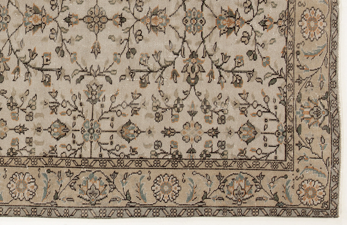 Beige rug with a traditional floral vine pattern in muted blue, orange, and charcoal, featuring a detailed border.