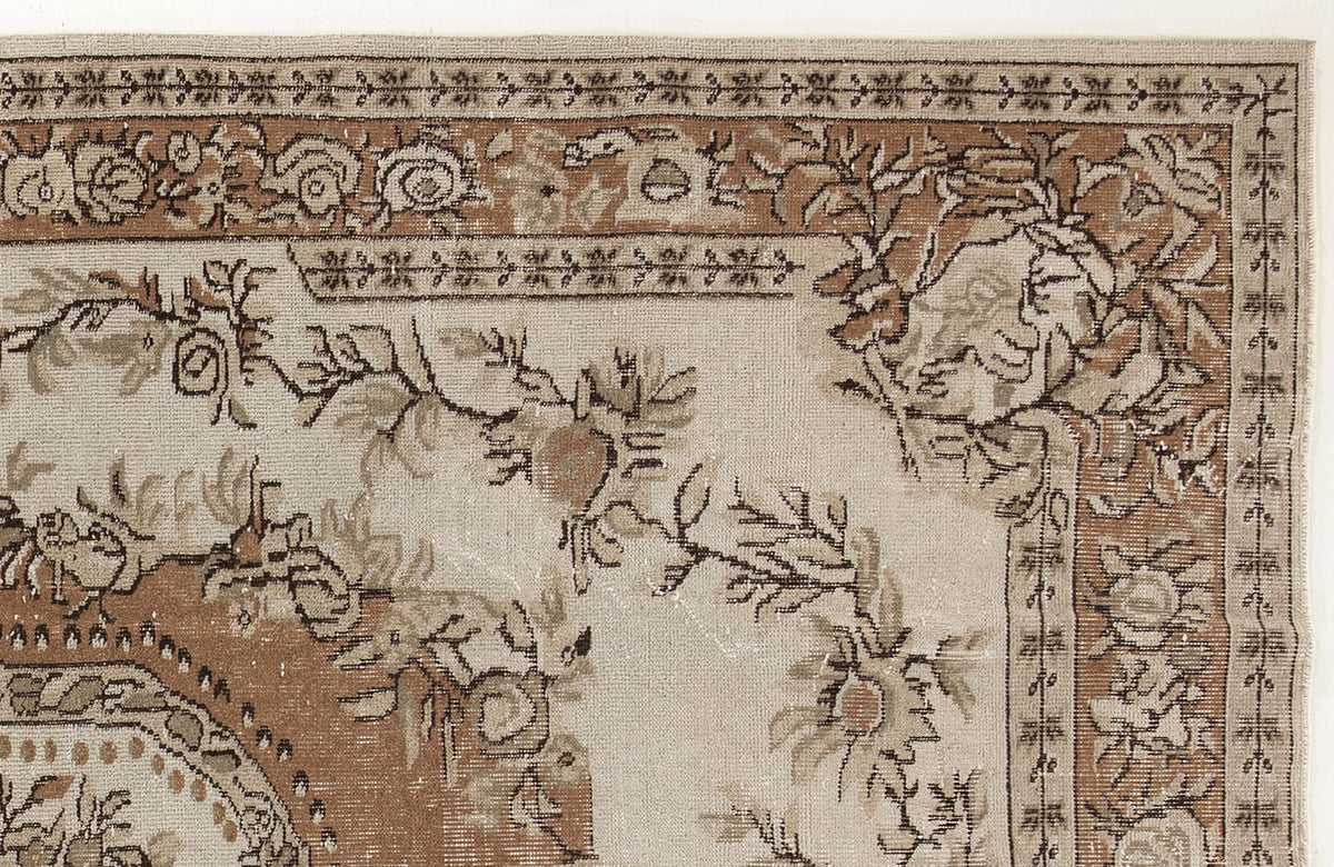 Beige and brown traditional rug with a floral medallion border and intricate vine motifs.