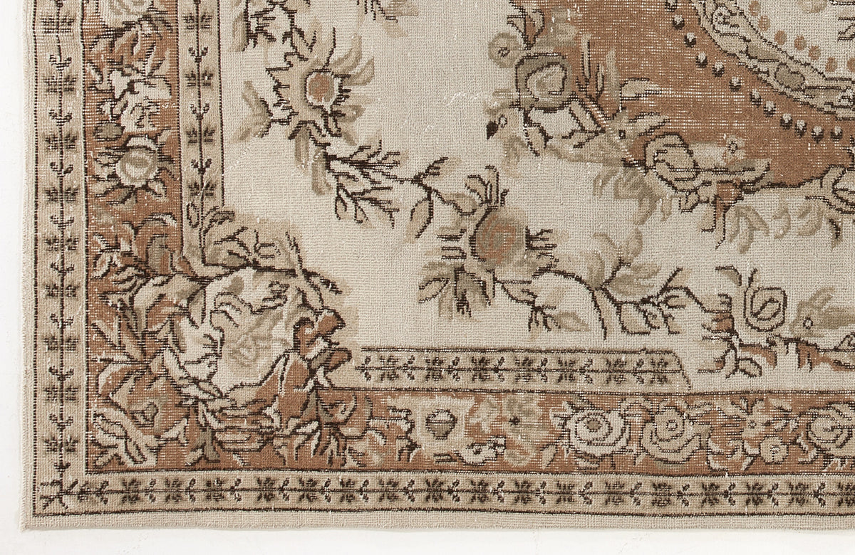 Beige and brown vintage-style rug with a floral medallion pattern and a detailed geometric border.