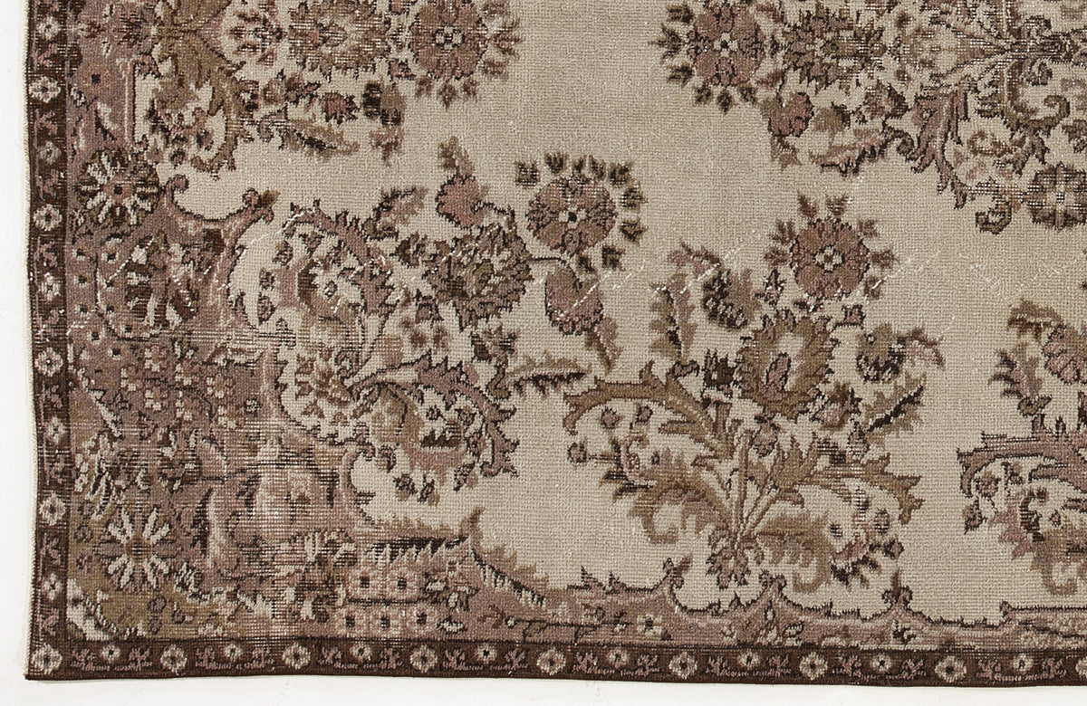 Beige and brown vintage-style rug with a distressed floral medallion pattern and a decorative border.