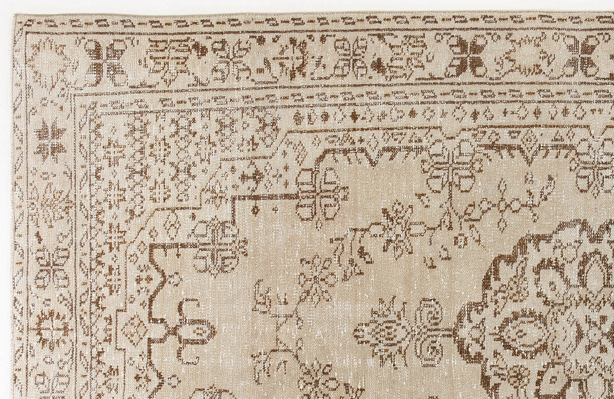 Beige and brown rug with a distressed traditional floral medallion pattern and geometric border.